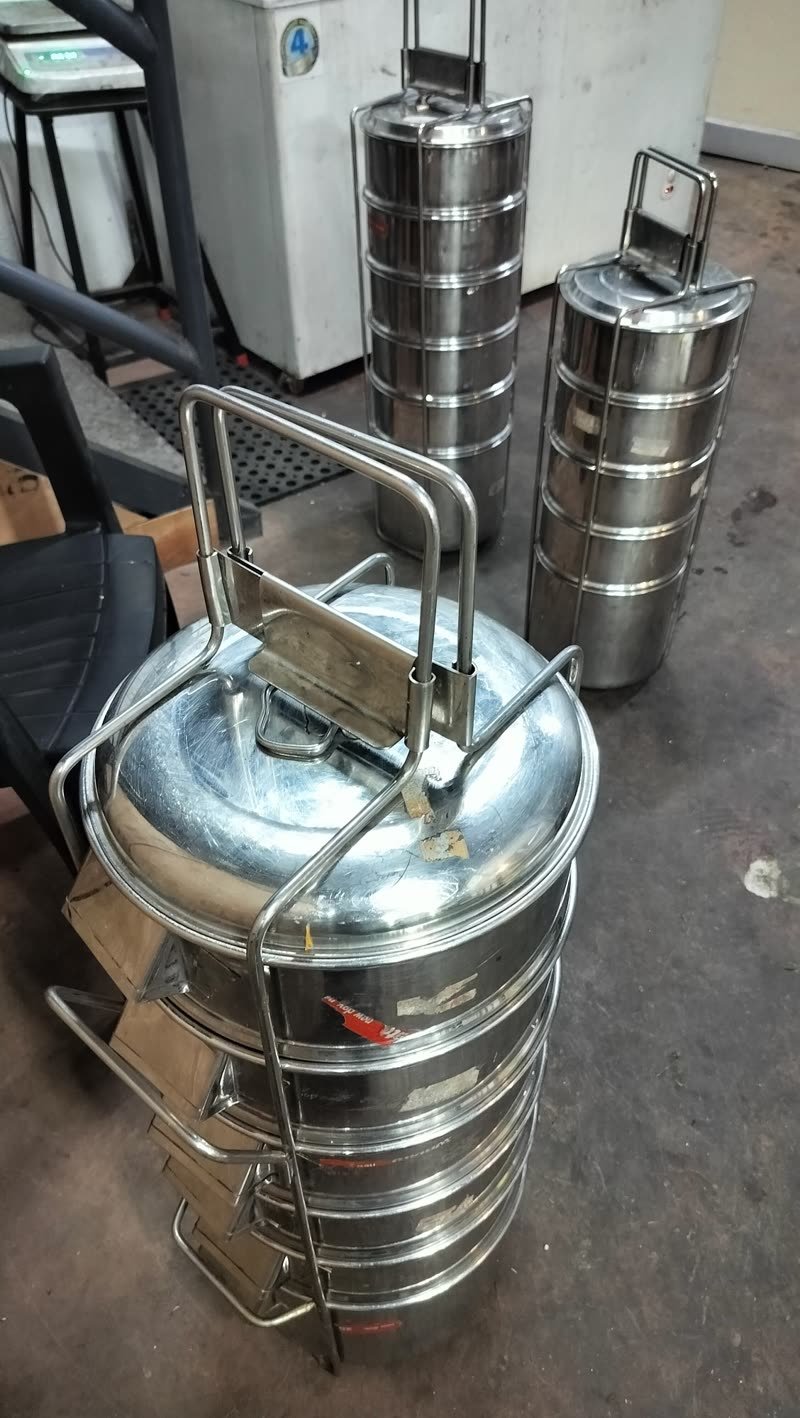 Stacked steel tiffin carriers in their wire frames, ready to go out