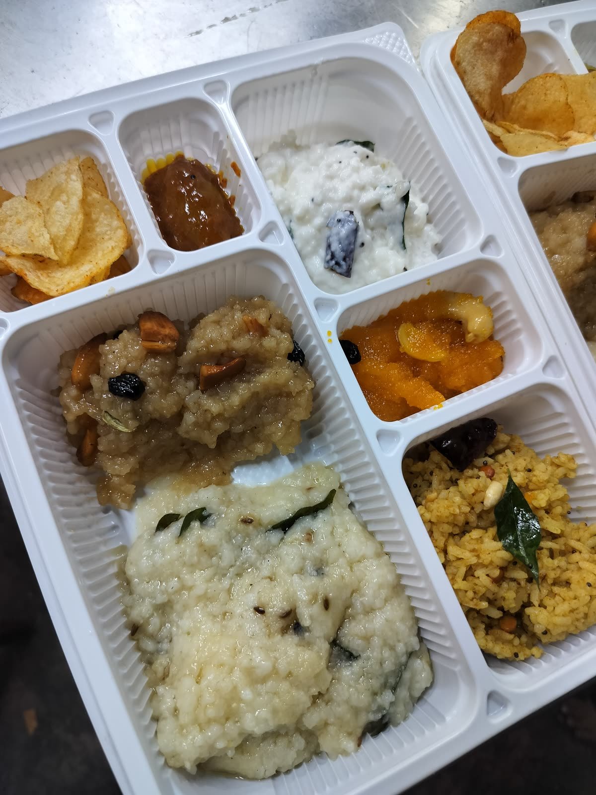 A full compartment meal tray with rice, curries, poriyal and a sweet